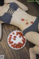 A woman laying on the floor next to a plate of tomatoes.