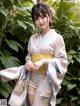 A woman in a pink and blue kimono posing for a picture.