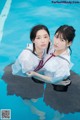 Two young women in school uniforms in a swimming pool.