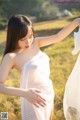 A woman in a white dress standing in a field.