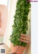 A woman sitting on a wooden bench next to a potted plant.