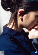 A woman in a blue shirt with her hand on her chin.