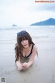 A woman laying on the beach in a bikini and sunglasses.