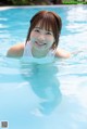 A young woman in a swimming pool smiling at the camera.