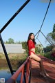 A woman in a red top and black pantyhose posing on a bridge.