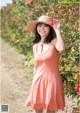 A woman in a pink dress and a straw hat smiles at the camera.