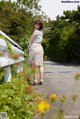 A woman standing on the side of a road next to a fence.