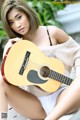 A woman sitting on a bench holding a guitar.