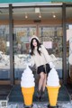 A woman standing next to two ice cream cones in front of a store.