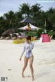 A woman in a bathing suit walking on a beach.