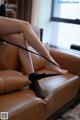 A woman sitting on a couch with her legs tied up.