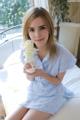 A woman sitting on a bed holding a white flower.