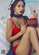 A woman in a red lingerie holding a cake.