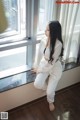 A woman sitting on a window sill looking out the window.