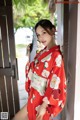 A woman in a red kimono holding a fan.