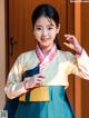 A woman in a blue and yellow hanbok posing for a picture.