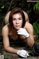 A woman in white gloves laying on a rock in the woods.