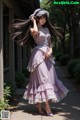 A woman in a purple dress is walking down a sidewalk.